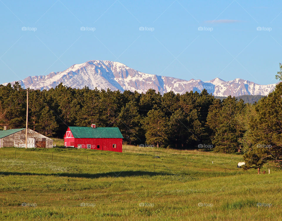 Red barn with a background of snow capped mountains
