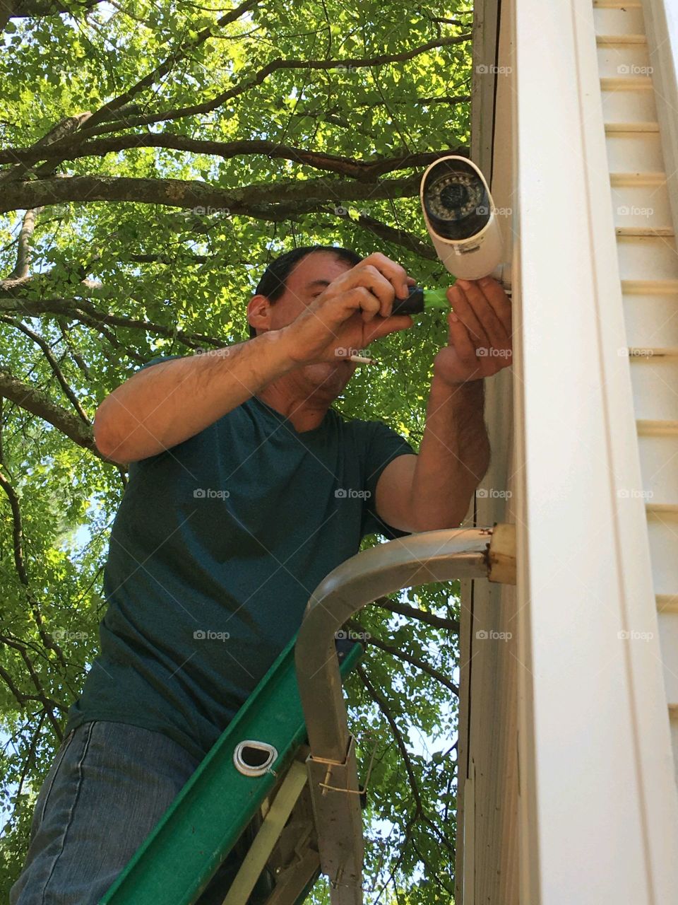 #stayathome - DIY projects
Man upgrading camera surveillance system in his home. He's standing high up on tall ladder as he adjusts angle.