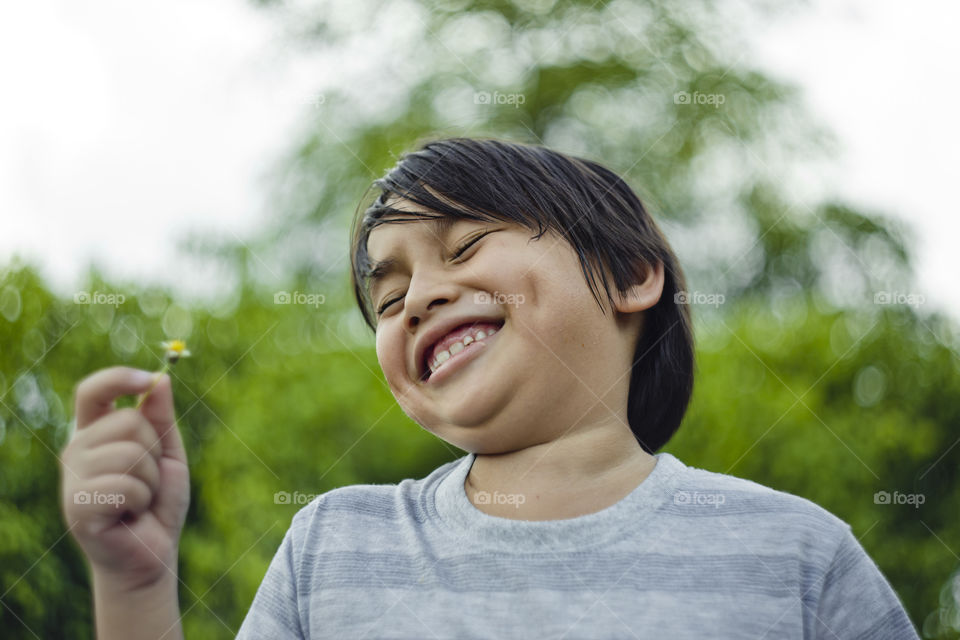 outdoor portrait of happy young eurasian boy on a blurry out of focus bokeh foliage background