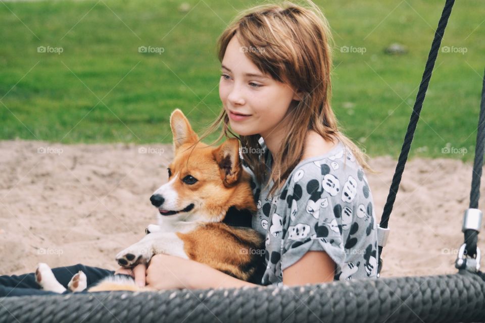 Girl and her cute dog sitting in a swing