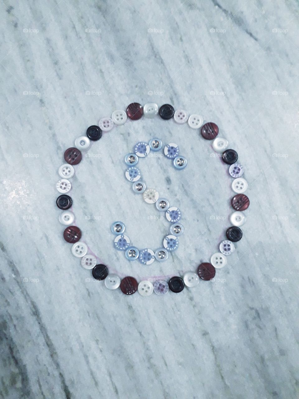S letter of english alphabet in round shape which is made of buttons. The shape of the Atlantic Ocean is similar to the letter S in English.