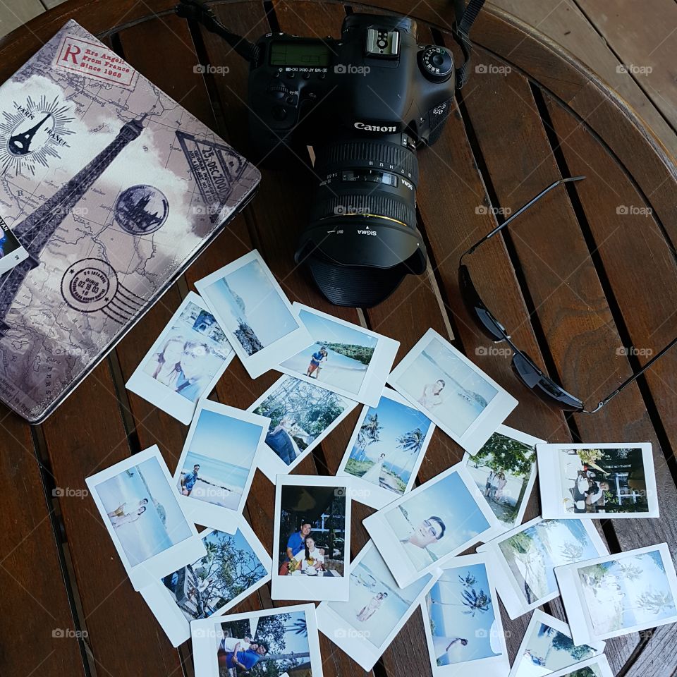 High angle view of photographs with camera on wooden table