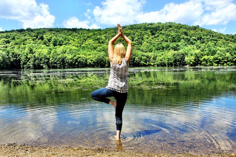 with one . Tree  pose in a lake surrounded by nature
