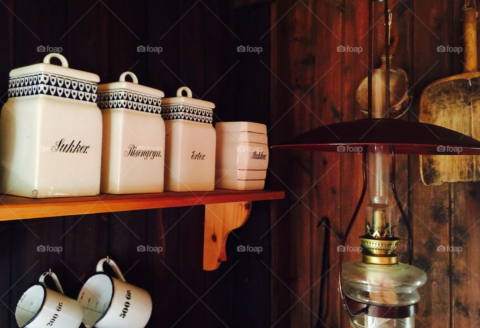 Ceramic containers on shelf with lamp and measuring cup
