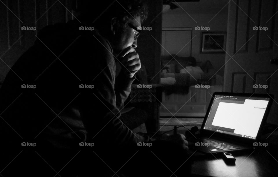 A man working on a laptop concentrating at home in black and white