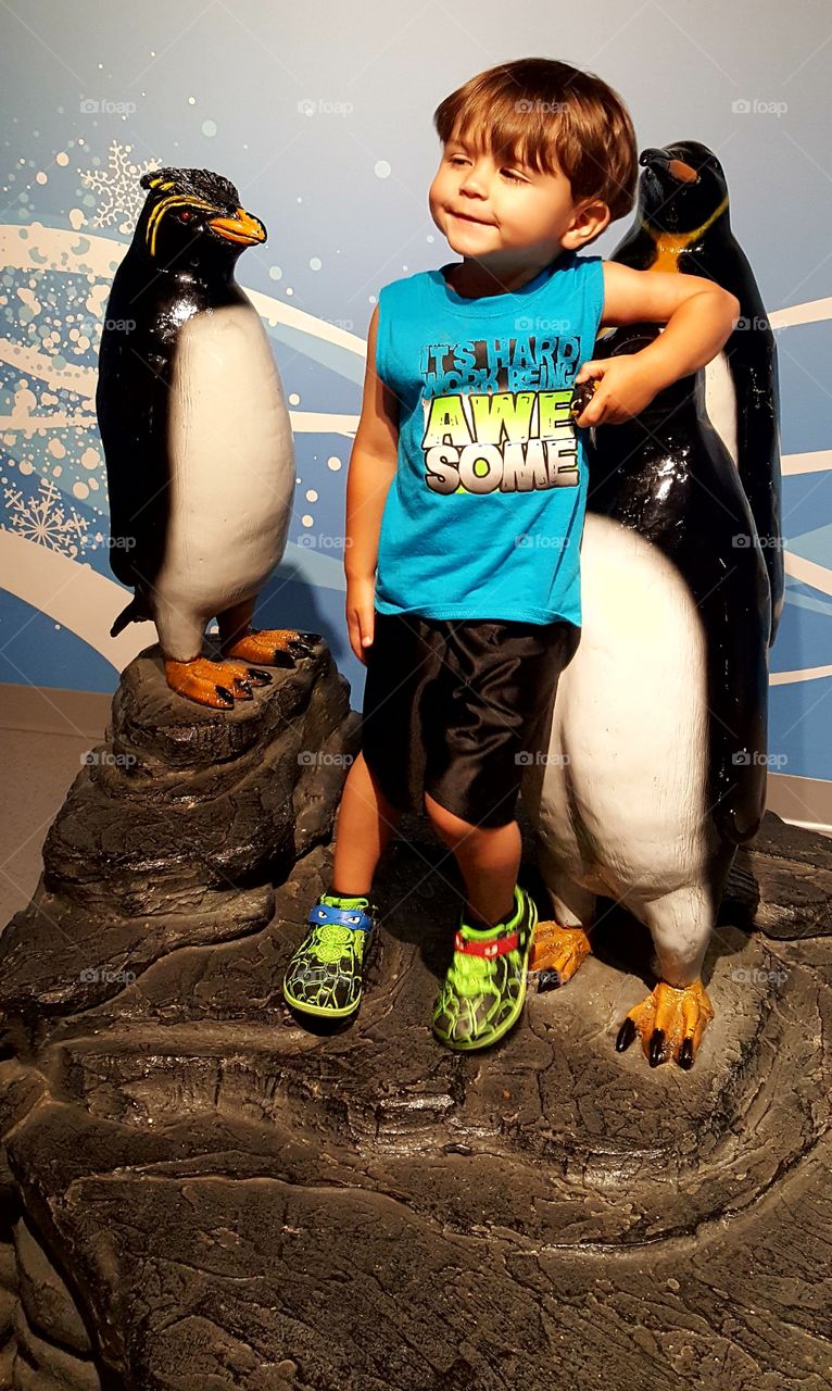 Boy posing with penguin statue
