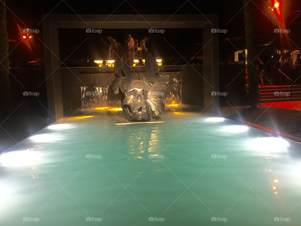 Swimming pool at night with a huge skull as decoration 