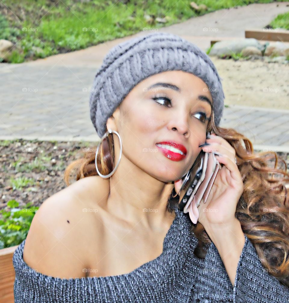 fashion modeling on the phone on a park bench outdoors
