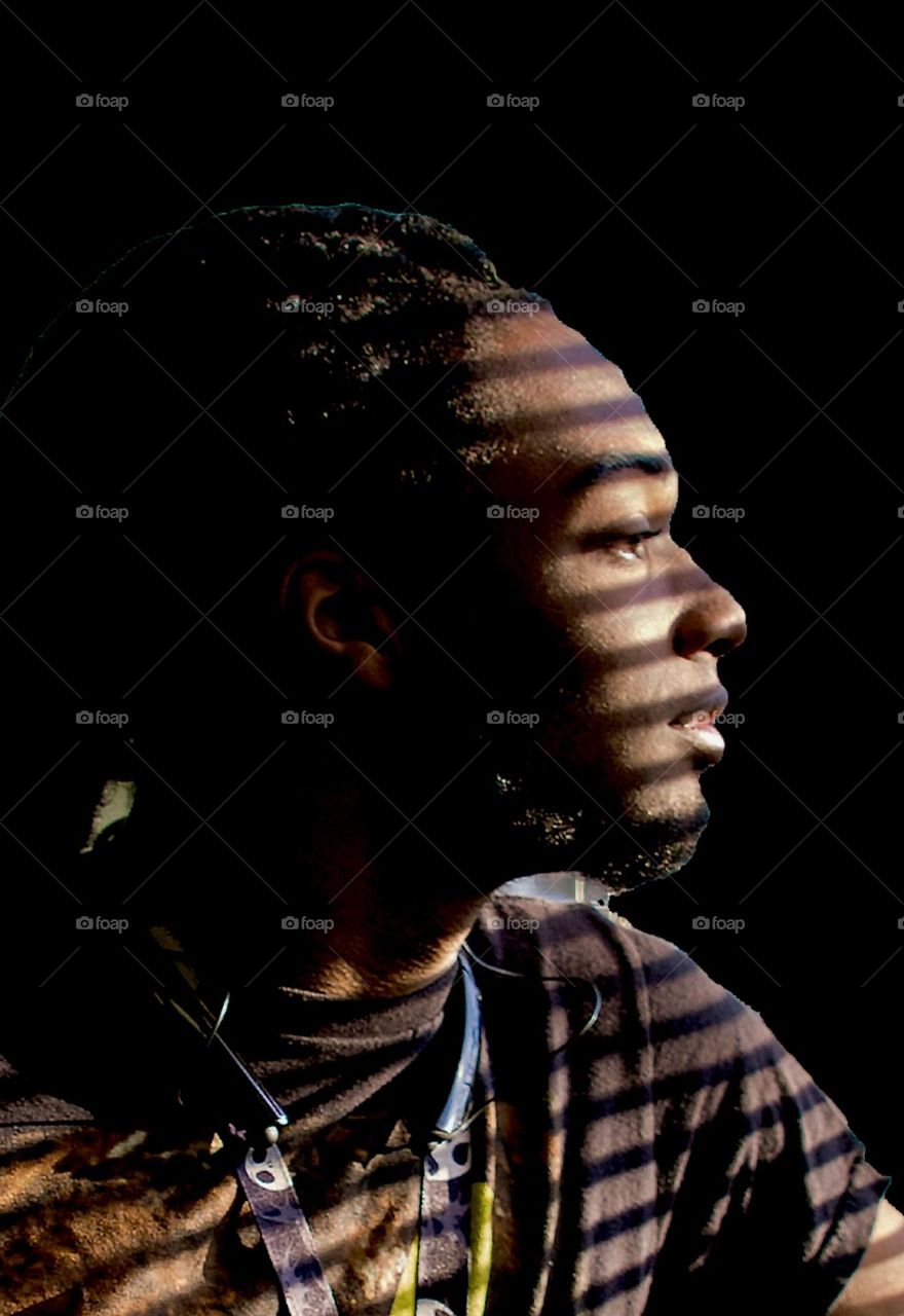 Young man looking through window blinds