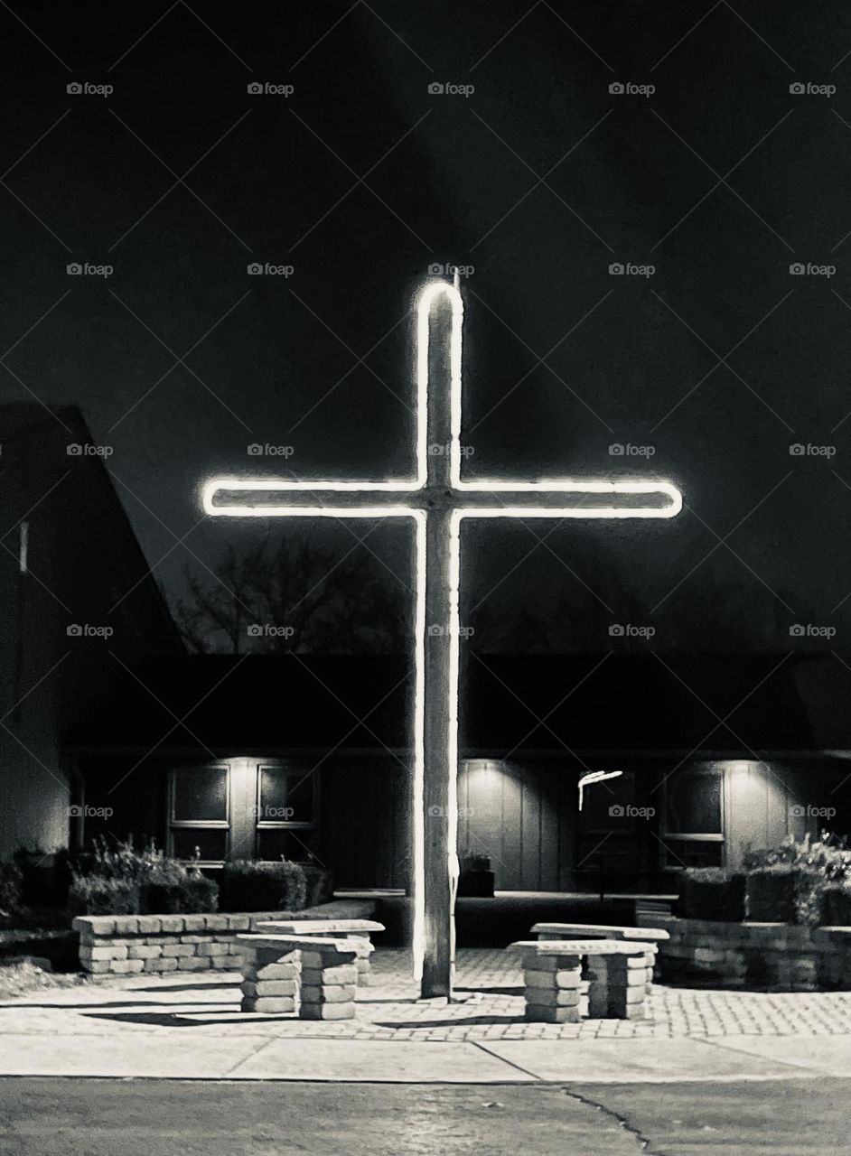 A lit cross at a local church, at night.