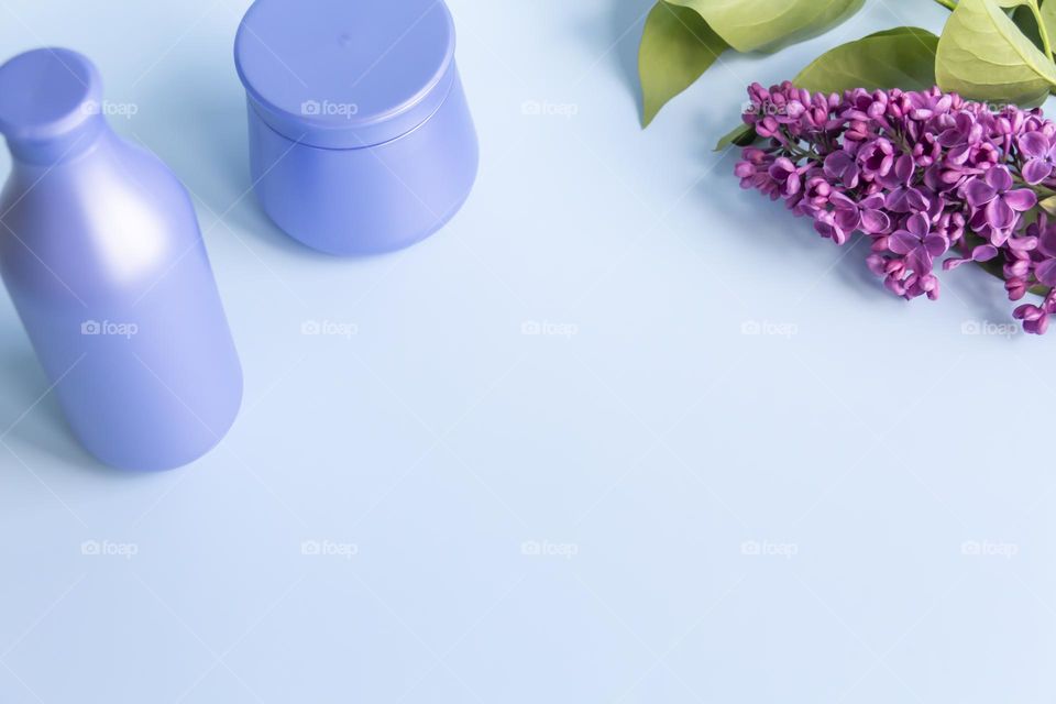 Spring, purple fragrant lilac with green leaves.  and jars with cosmetic cream and product.