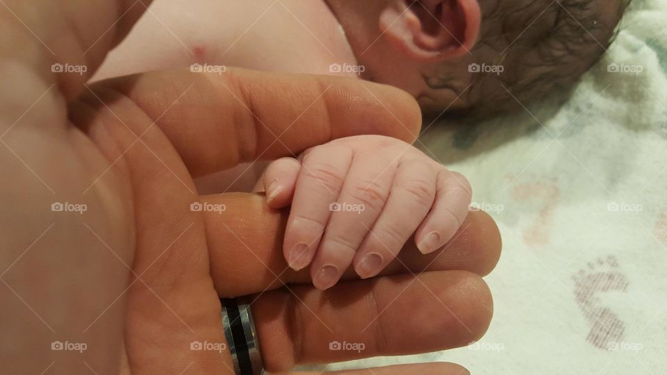 Father holding his newborn son's hand