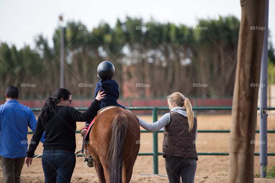 coah and a mother hoding a child riding a horse in a riding class