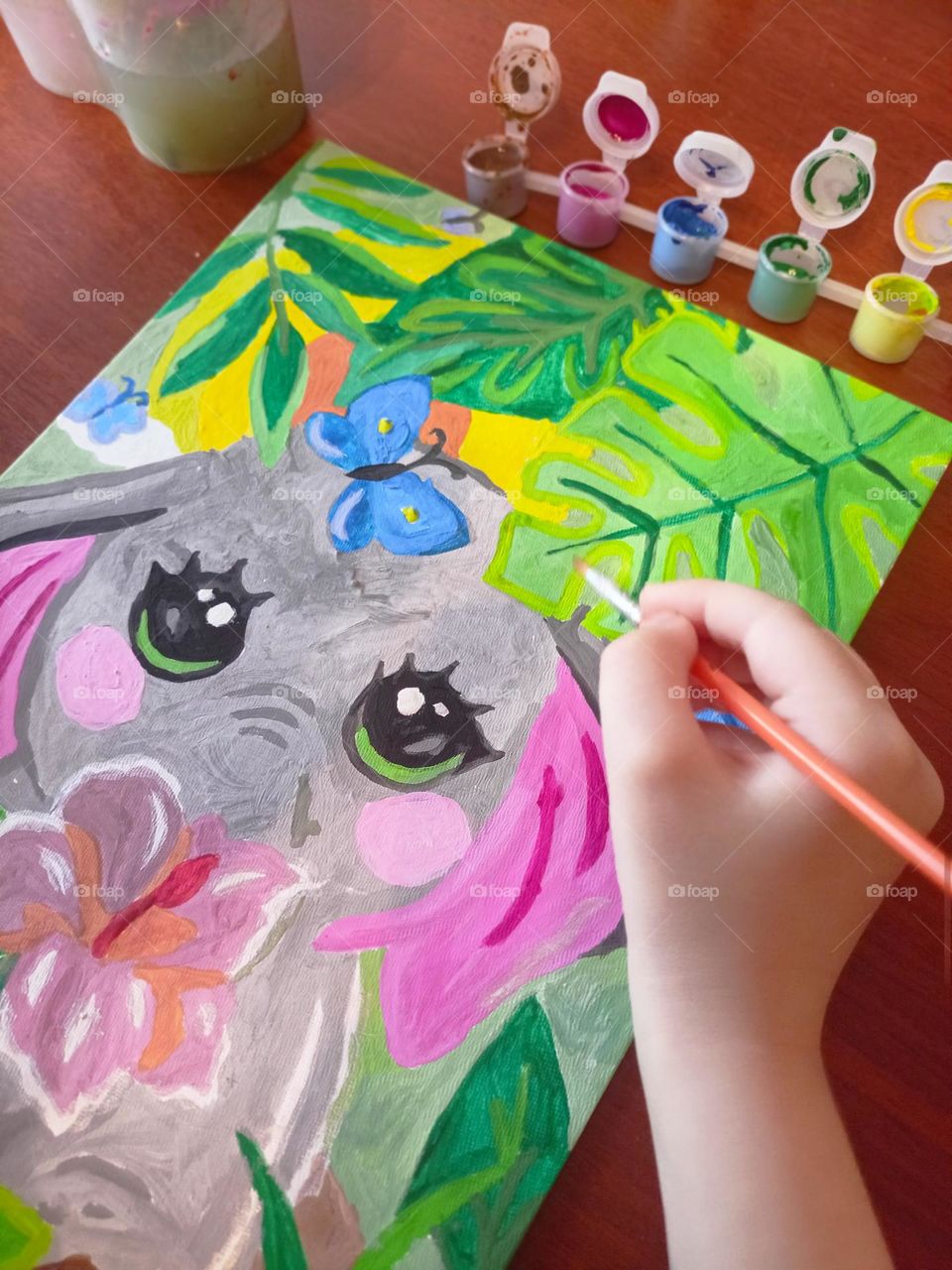 girl paints a baby elephant, child's hand, brush, paints, gouache drawing, bright drawing, gray, pink, green, picture, young artist,