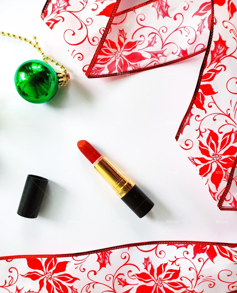 A vivacious red lipstick flatlay in a red, white and green holiday inspired theme.