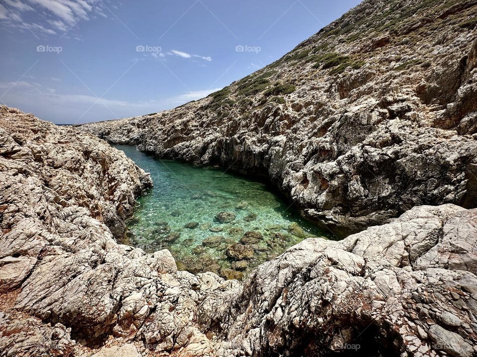 Clear blue waters and rocky shoreline of Katholiko Bay, Crete, Greece