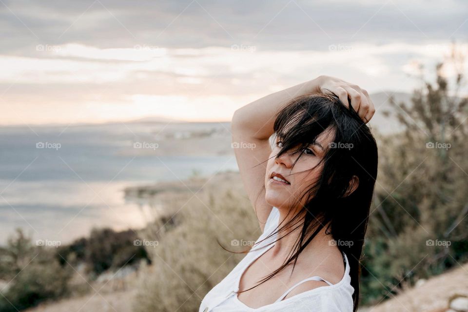 Portrait of beautiful young woman with wind in hair on the coast of sea