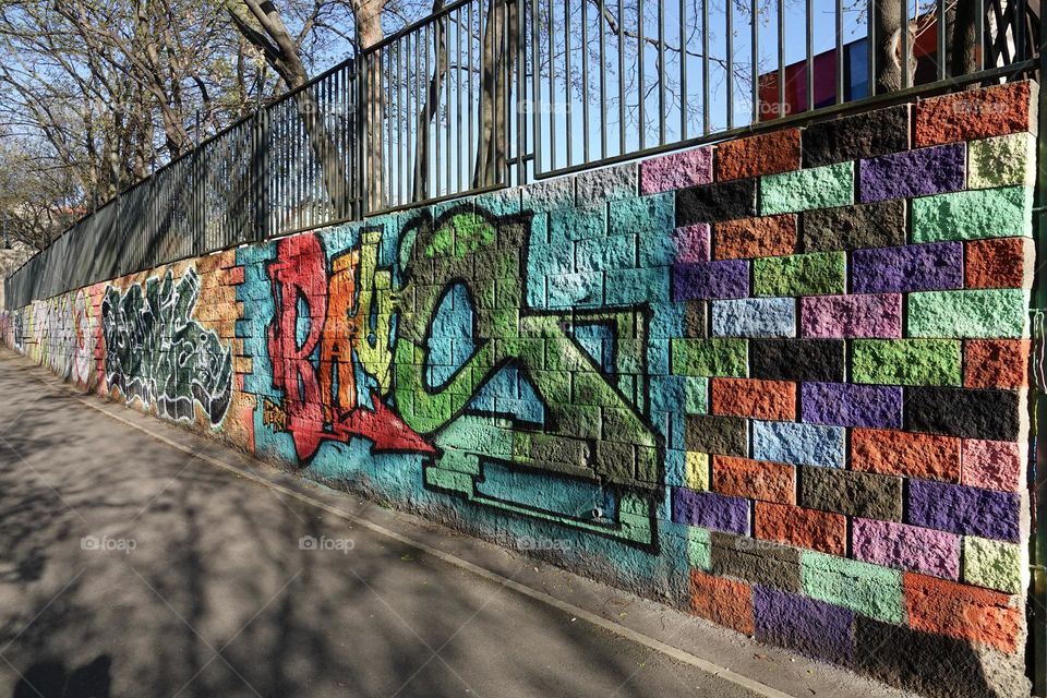 Colorful abstract graffiti and lettering on the brick wall by the path in Krejcarek park in Prague, Zizkov.