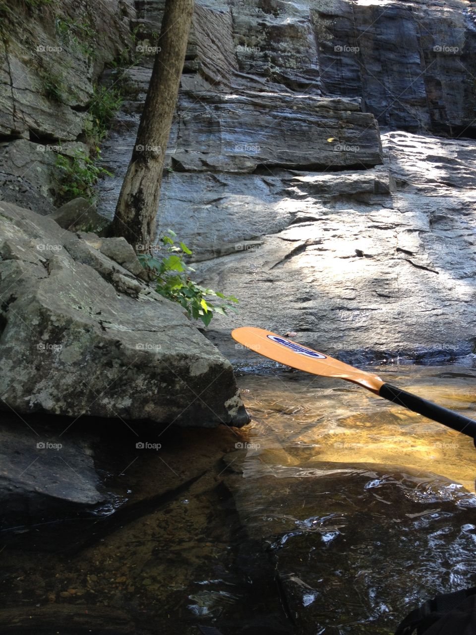 A paddles view. Still water and rocks 