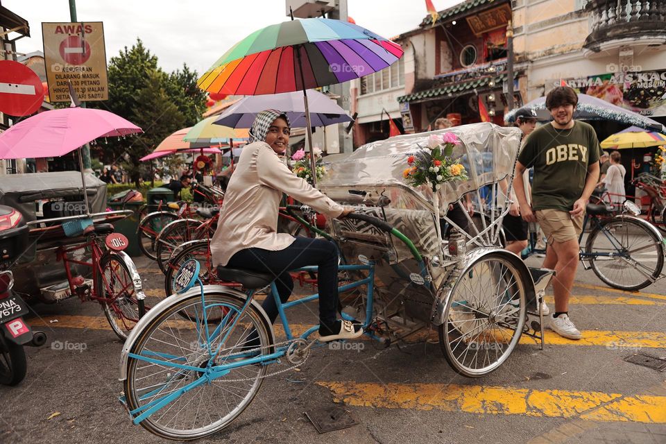 Young girl working as trishaw peddler at famous Armenian Street in Penang, Malaysia. This trishaw is popular among the tourists.