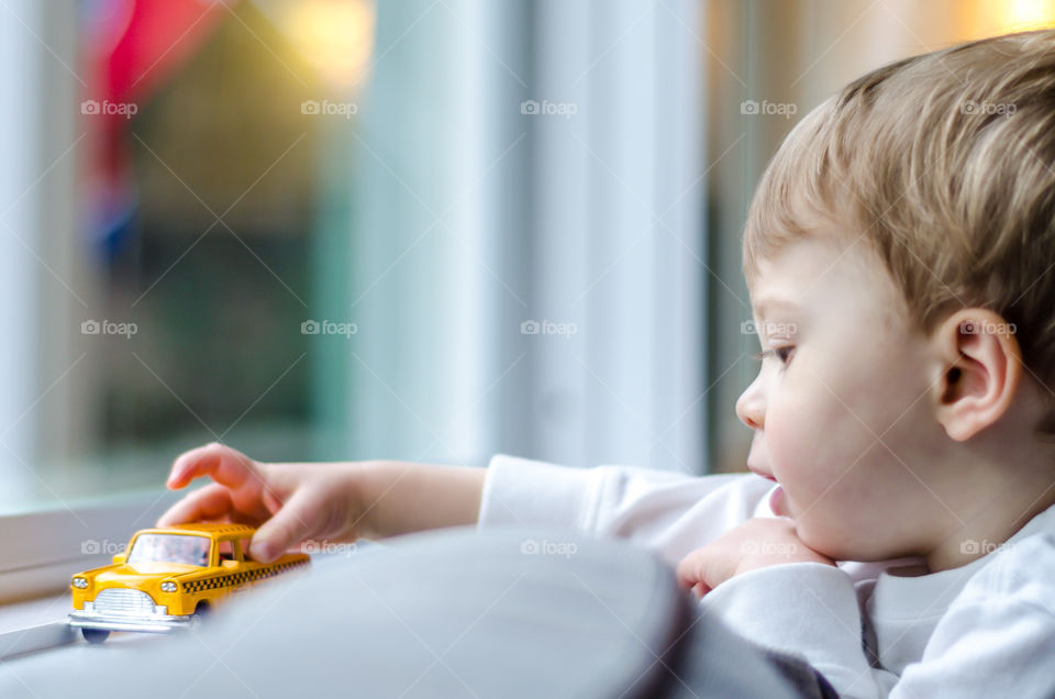Boy playing with toy car on window