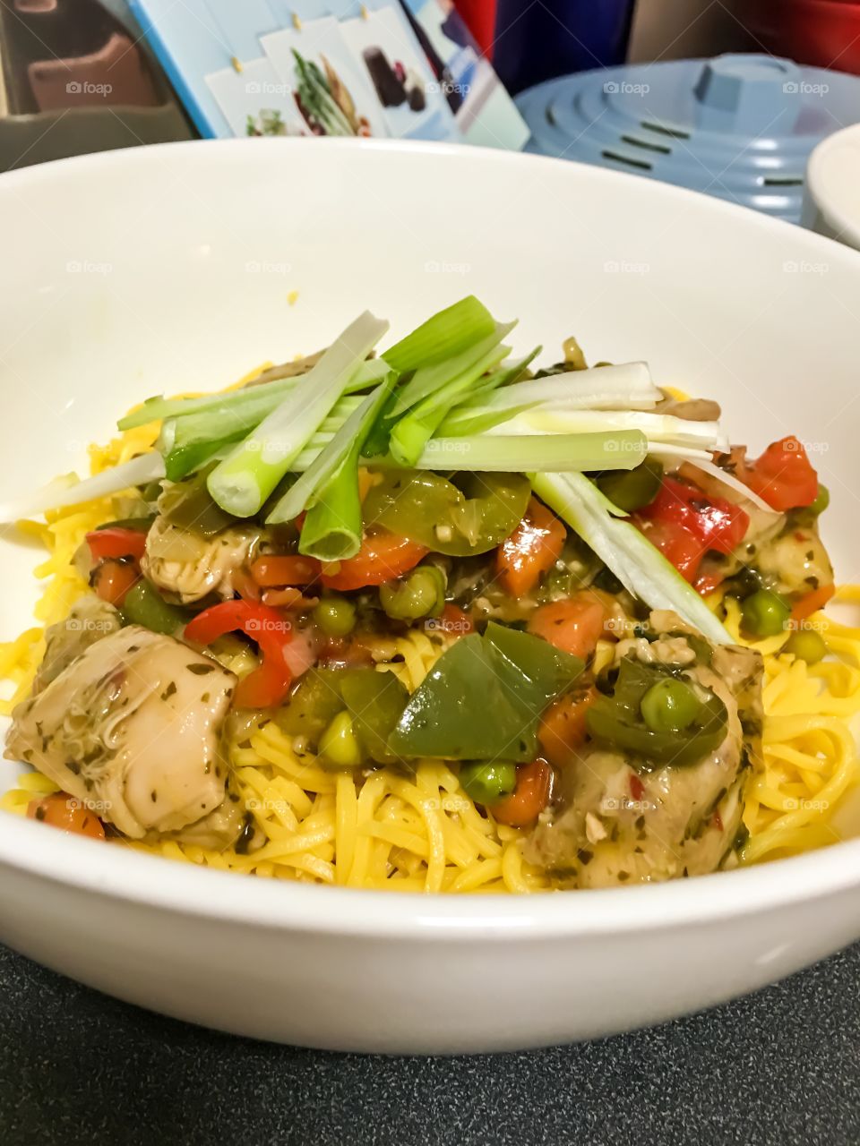 Thai food, basil chilli chicken and vegetables on Singapore noodles closeup Asian food in white bowl chopsticks