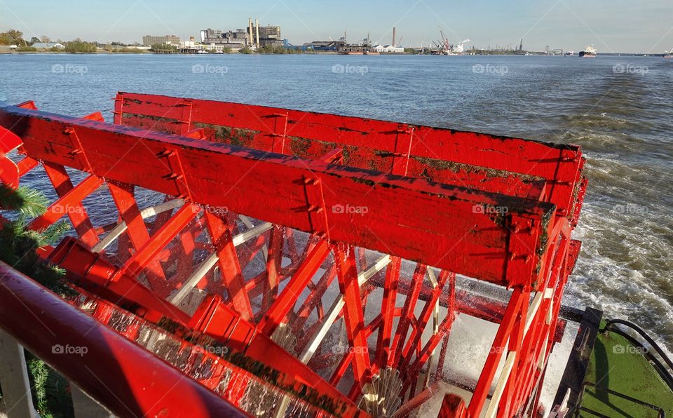 Bright red cylindrical paddles of the steamboat Natchez. Waves trailing behind is the Mississippi River. New Orleans, Louisiana, USA.