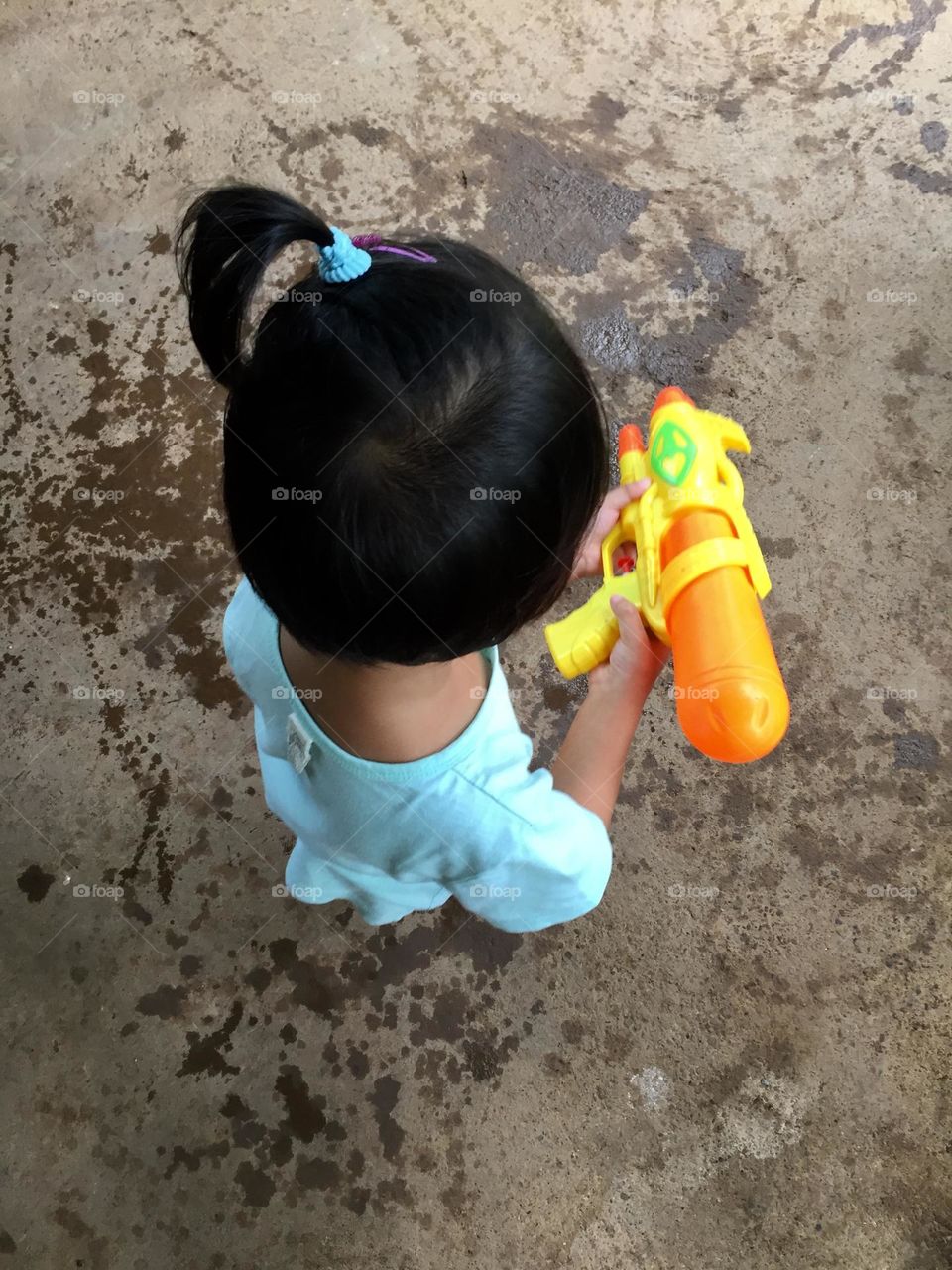Toddler girl playing water gun 