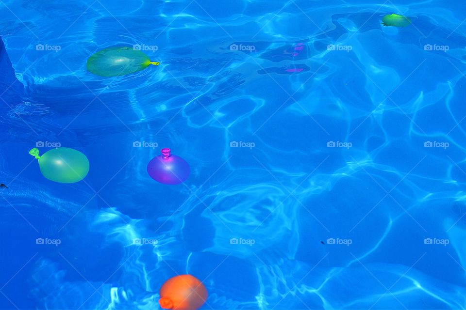 Water balloons floating. Colourful water-filled balloons floating in swimming pool