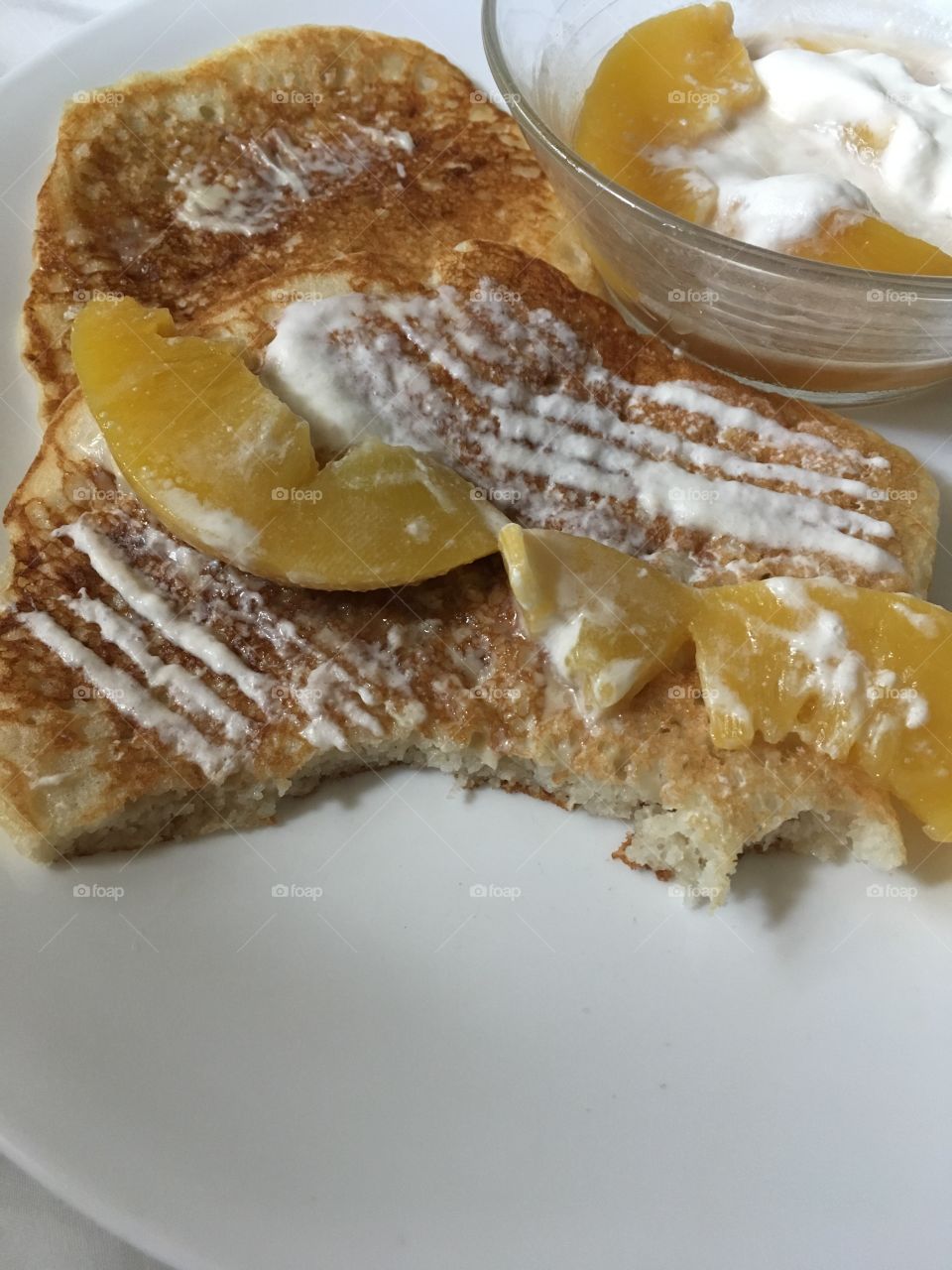 Delicious cinnamon pancakes coated in homemade whipping cream and fresh peaches 