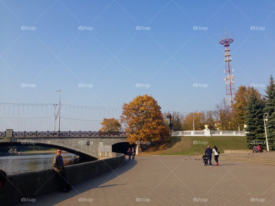 People walking in city central kids park in Minsk, bridge and street view