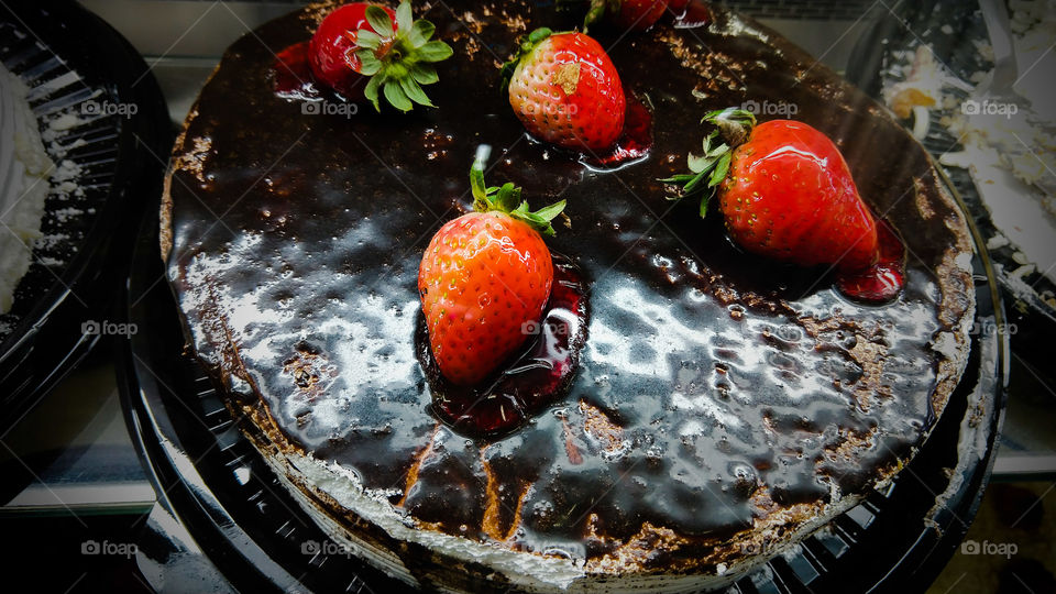 Confeitaria, bolo delicioso com recheios doces e coberturas de chocolate escuro e morangos.