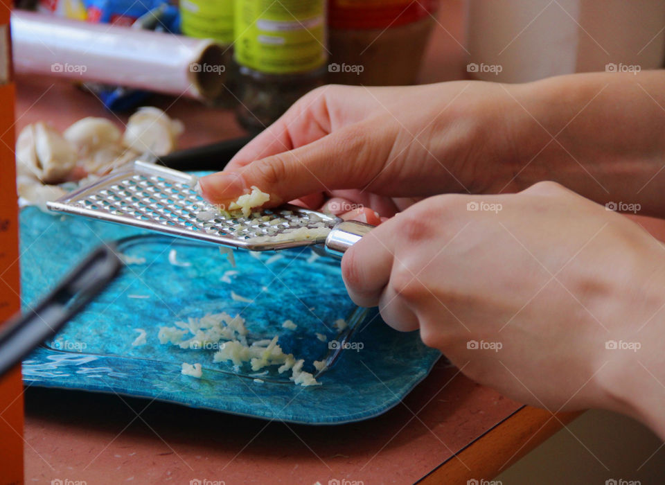 Person grating garlic with metal grater