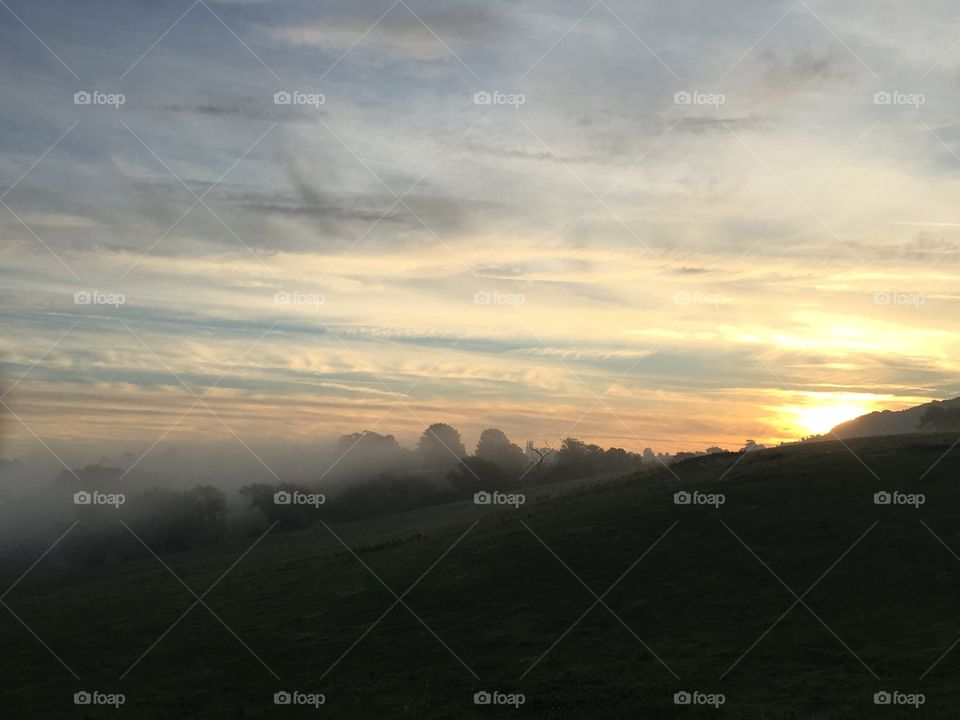 Cloudy sky over grassy land at sunrise