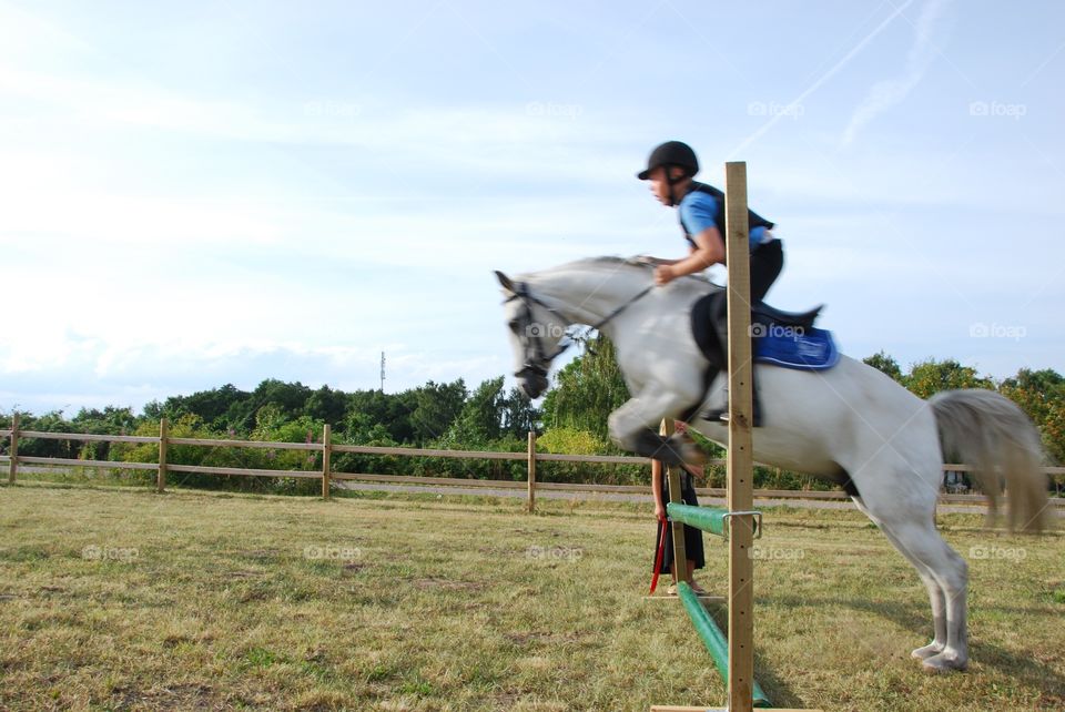 Male horse rider jumping over hurdle