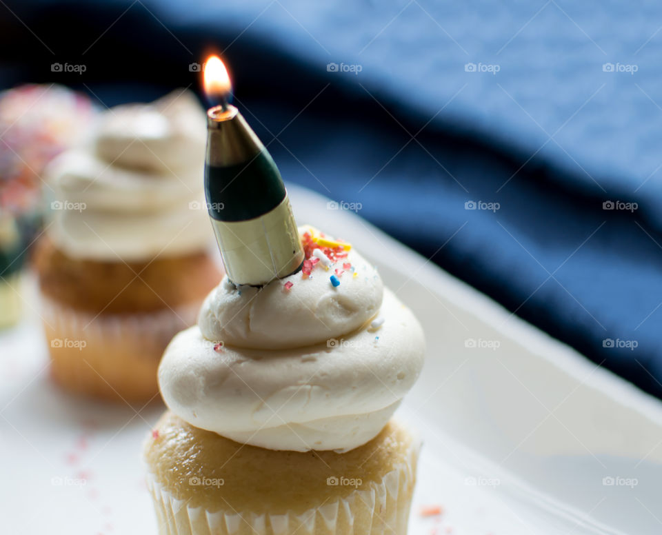 Celebration cupcake with champagne candle conceptual background to celebrate success and milestones