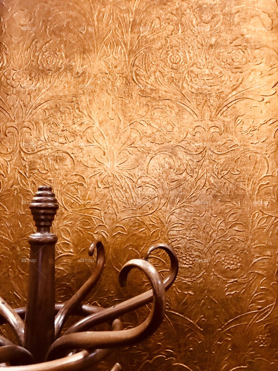 Hatstand against a golden patterned wall