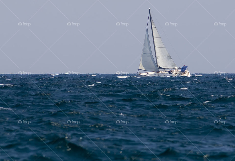 White yacht in blue waves with white crests