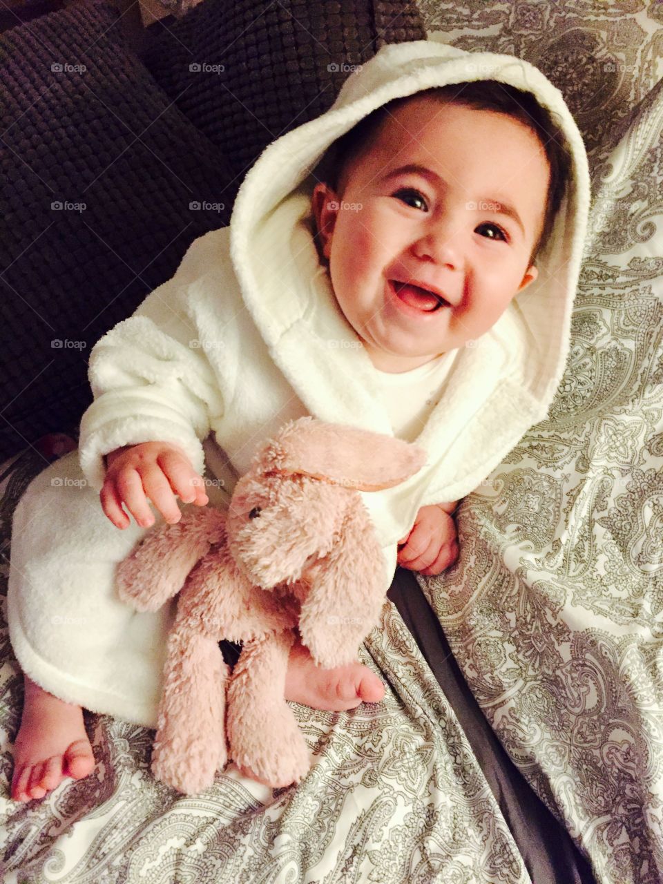 Smiling baby girl in a white fluffy robe