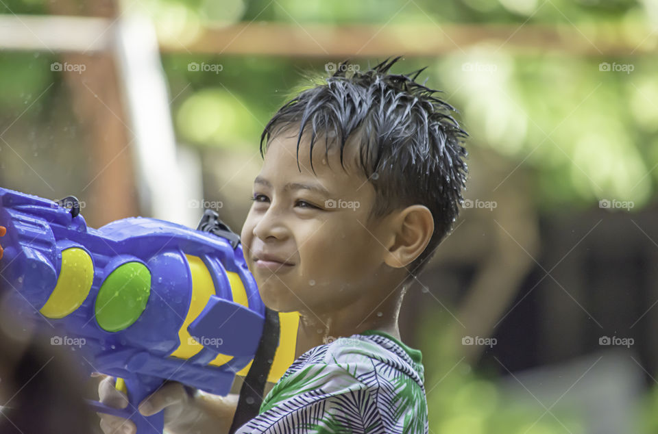 Asian boy holding a water gun play Songkran festival or Thai new year in Thailand.