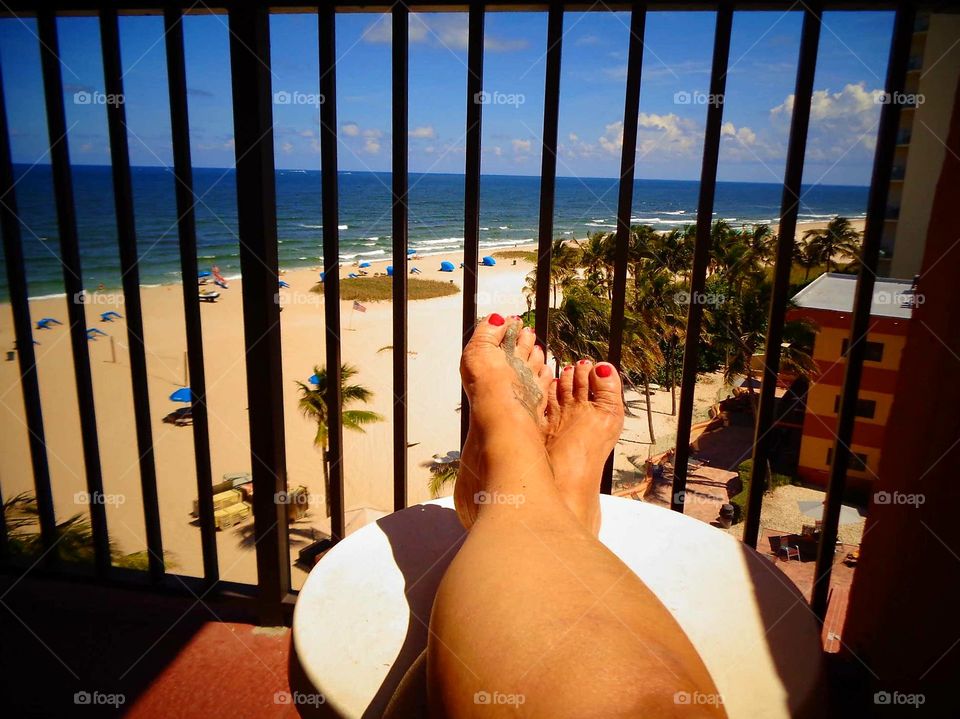 Sunbathing with feet up on deck high above sand & ocean.