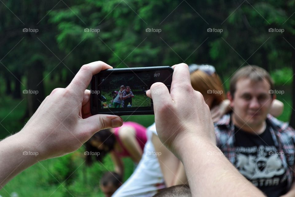 Close-up of human hand taking photograph of a couple