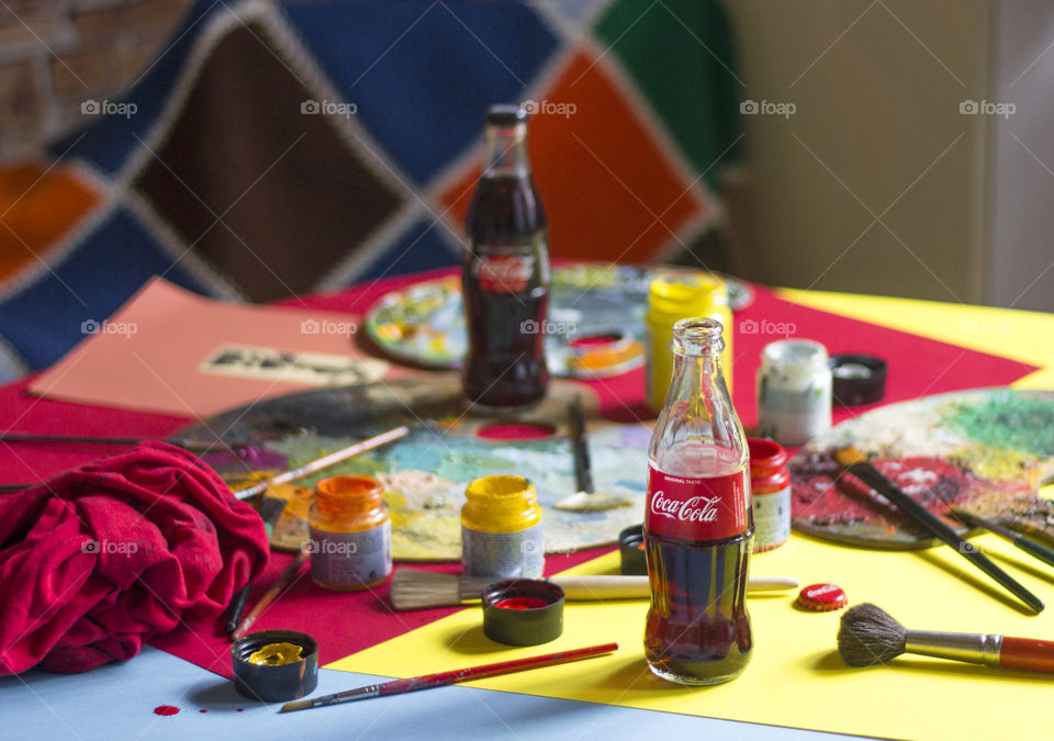 Coca-Cola bottles and colorful painting materials on the table