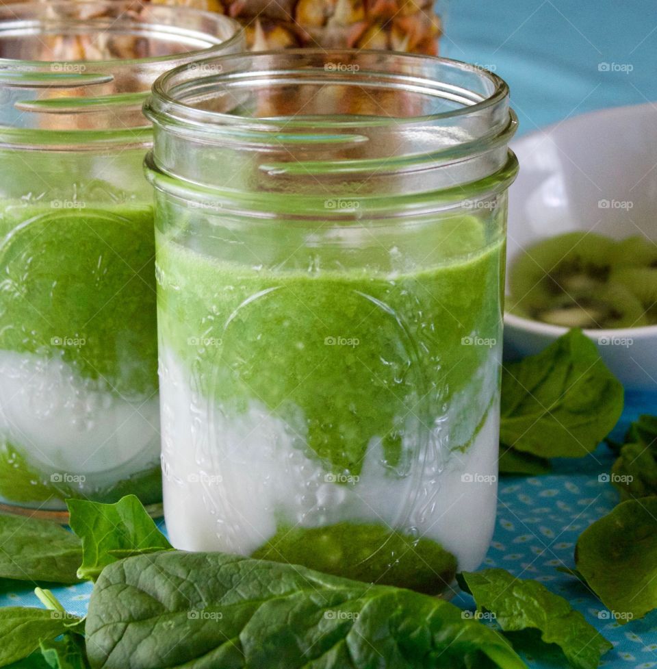 Fresh Fruit Smoothie -two spinach, kiwi, coconut milk and pineapple smoothies in pint canning jars on a turquoise tablecloth 