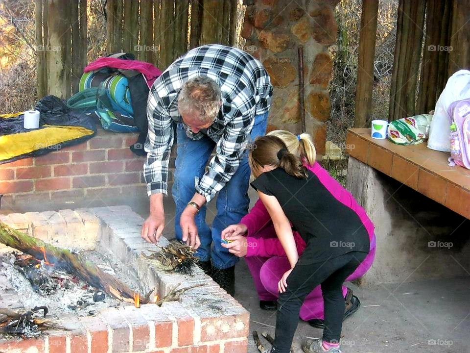 Grandfather is teaching how to make a fire