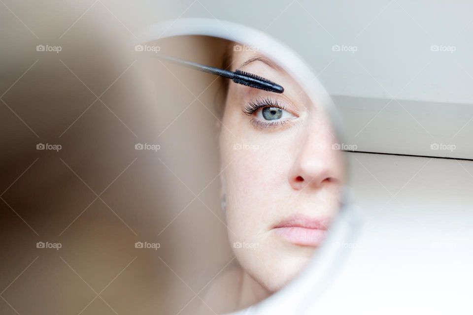 Beautiful woman applying mascara to her eyes
