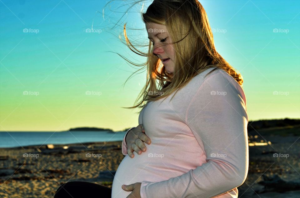 Beautiful pregnant woman sitting on beach