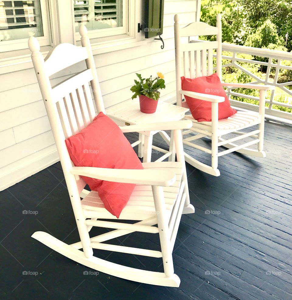 Orange pillows on white rocking chairs