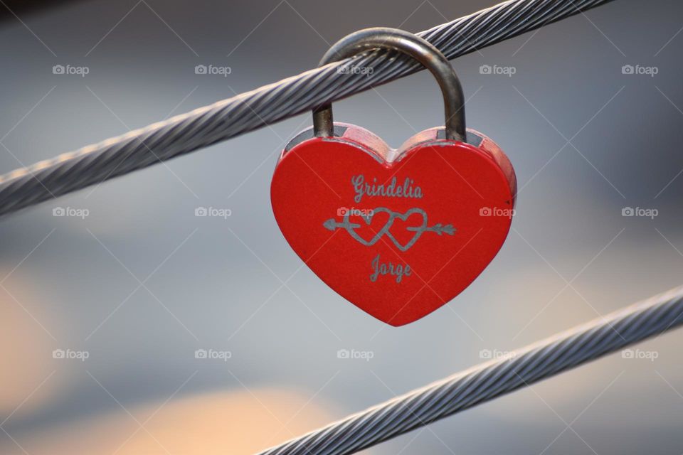Two people show their love on a heart lock