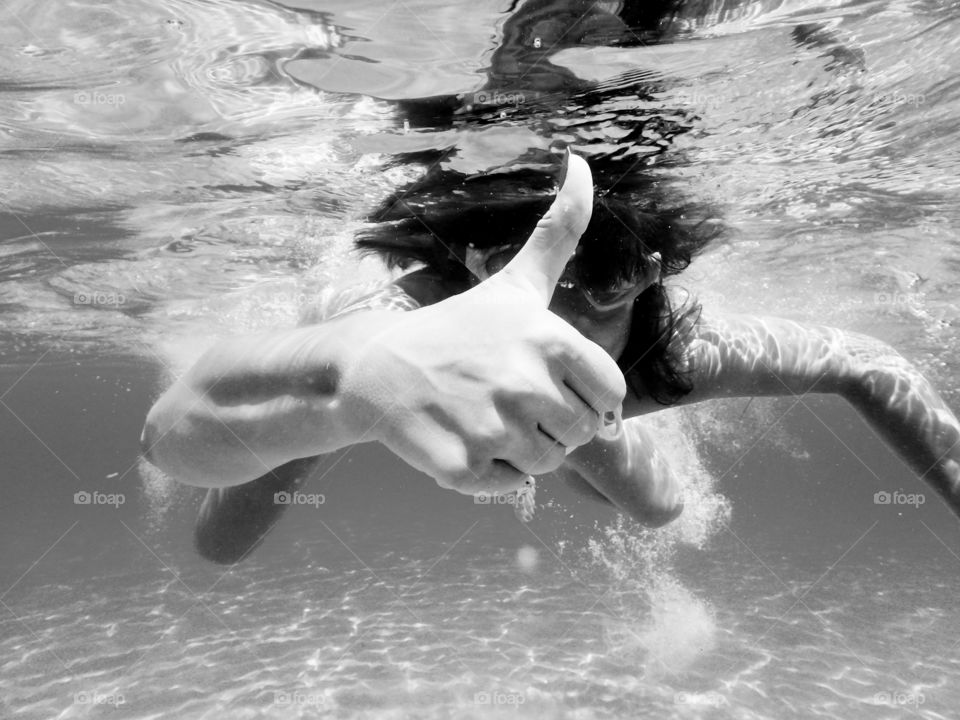 Woman underwater giving thumbs up in black and white photo